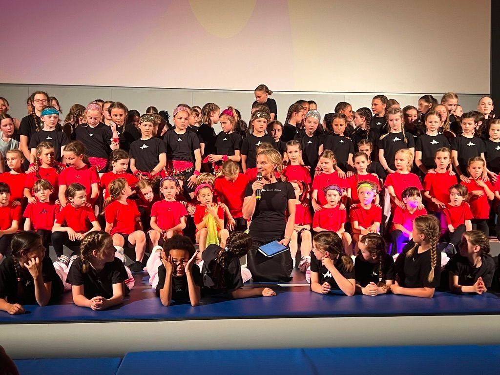 Große Kindergruppe in Rot und Schwarz mit Monica Czech am Mikrofon