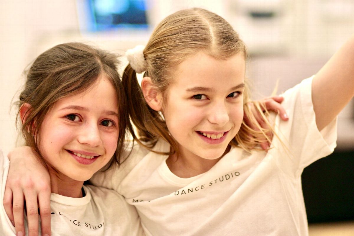 Zwei Mädchen in hellen Studio-Shirts, Arm in Arm