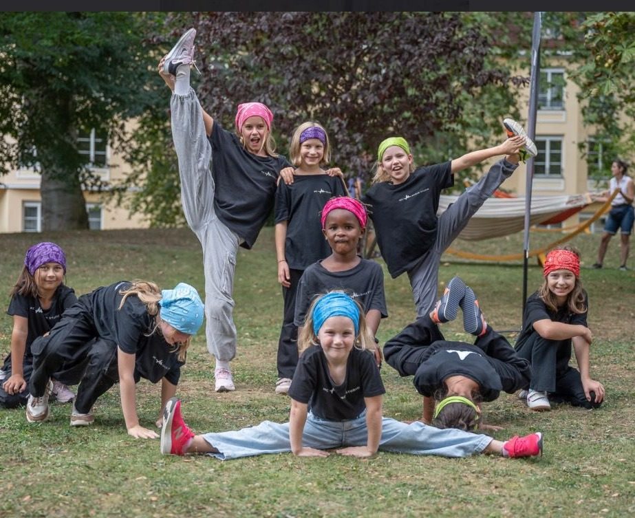 Kindergruppe mit bunten Bandanas in Akrobatikposen im Park