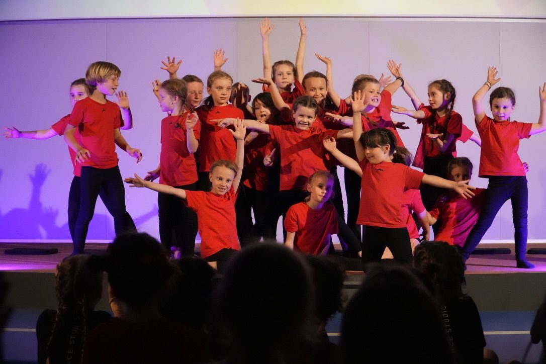 Kindergruppe in roten Shirts jubelt auf der Bühne