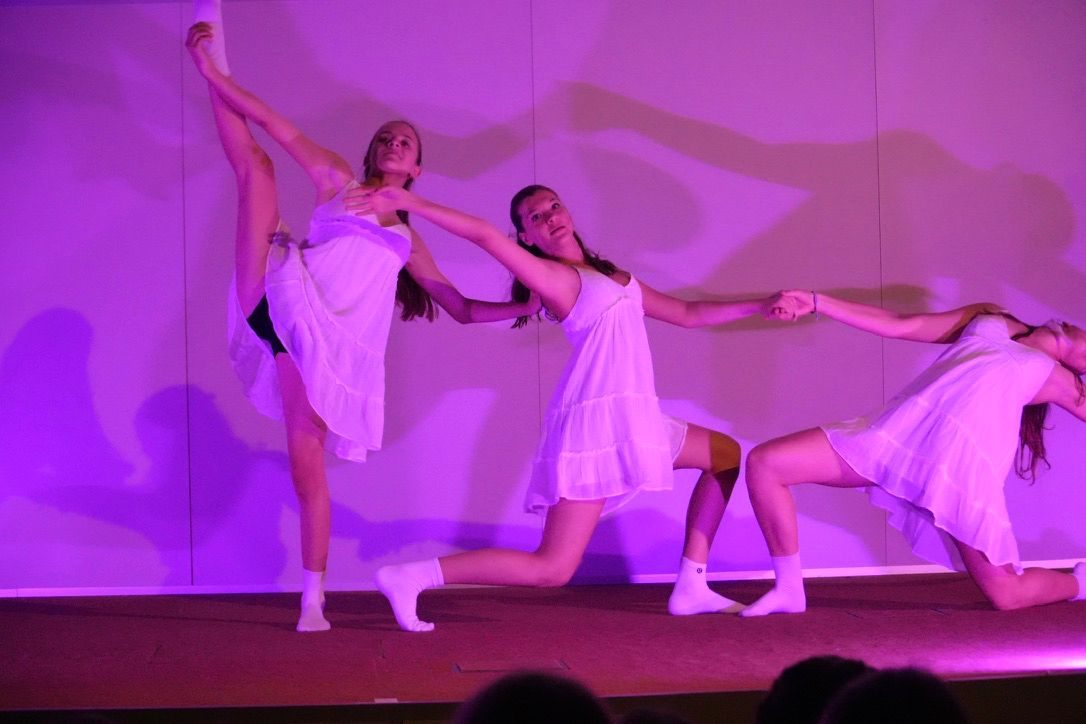 Drei Tänzerinnen in weißen Kleidern in einer Modern-Dance-Figur