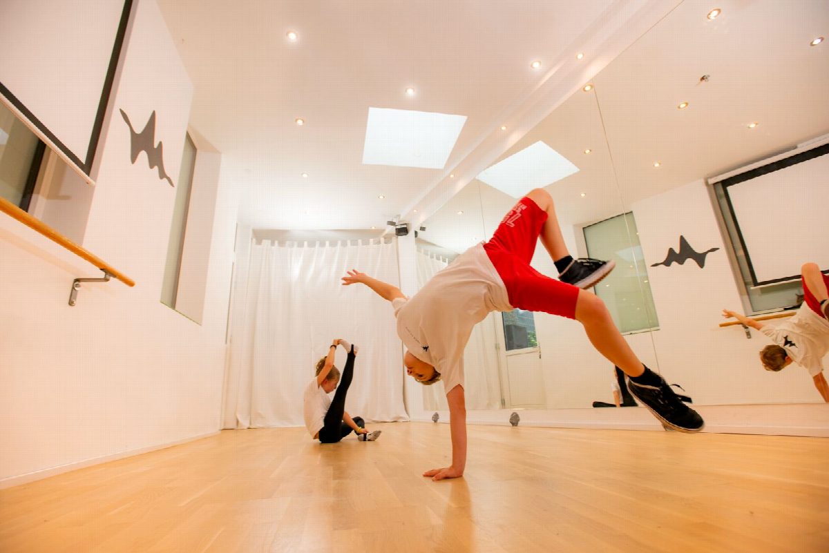 Ein Junge im Breakdance-Freeze, gestützt auf eine Hand